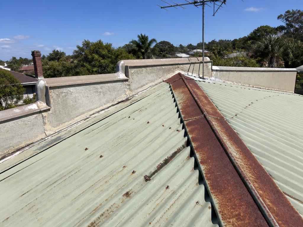 Old pale green corrugated metal roof with heavy rust along the sheets and fixings
